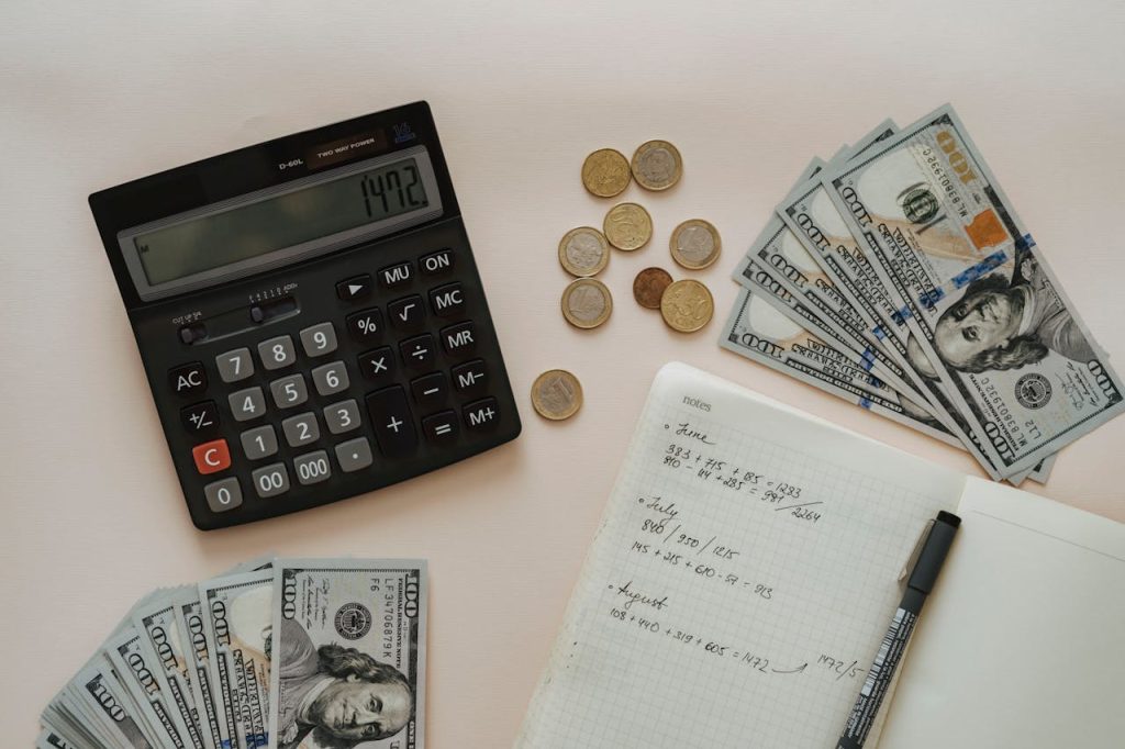 Flat lay of calculator, cash, coins, and handwritten notes for budget planning.